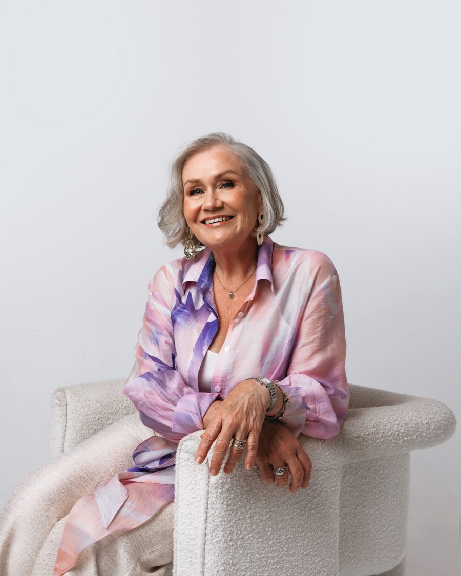 Deidre Brooker seated in an armchair, smiling